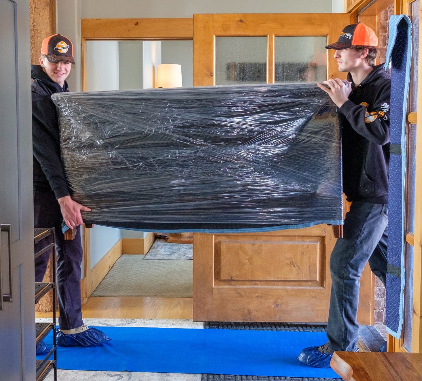 Two movers carefully carrying a padded dresser
