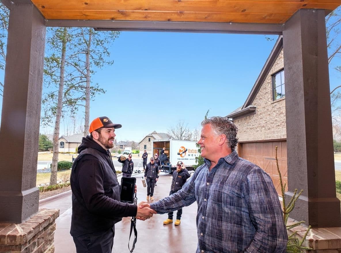 Customer shaking hands with Extra Mile Moving owner outside their home